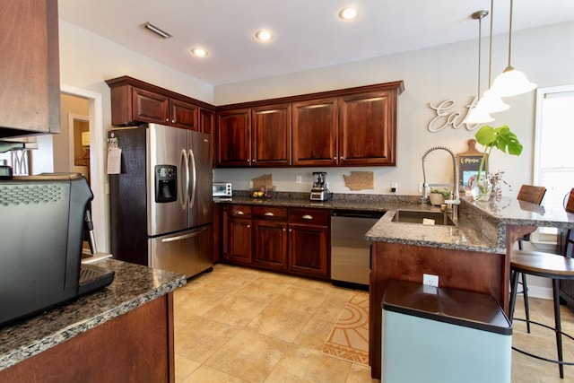 kitchen featuring a sink, a kitchen breakfast bar, stainless steel appliances, decorative light fixtures, and a peninsula
