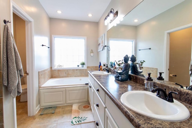 bathroom featuring plenty of natural light, a sink, a garden tub, and tile patterned floors