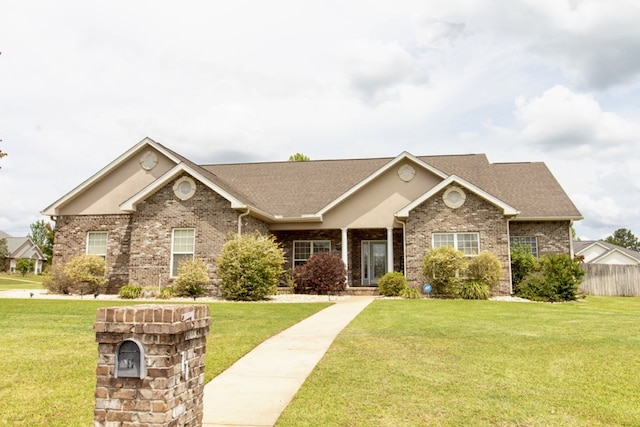 view of front of property featuring brick siding, roof with shingles, and a front yard