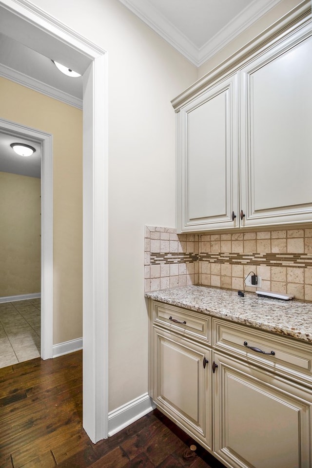 bar with crown molding, light stone countertops, dark hardwood / wood-style floors, and backsplash