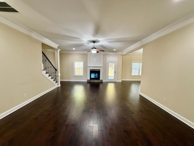 unfurnished living room featuring crown molding, dark wood-type flooring, decorative columns, and ceiling fan