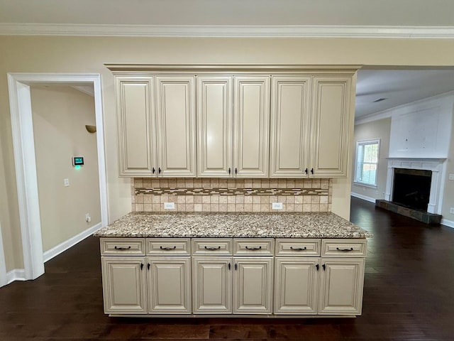 kitchen with tasteful backsplash, light stone counters, ornamental molding, and dark hardwood / wood-style floors