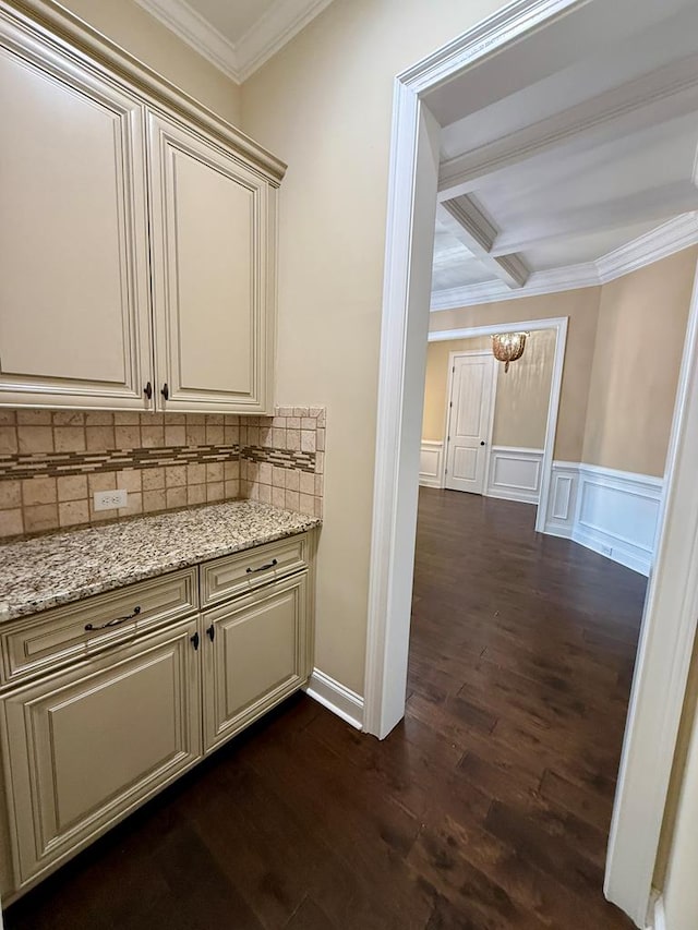 interior space with coffered ceiling, light stone counters, ornamental molding, dark hardwood / wood-style flooring, and beamed ceiling