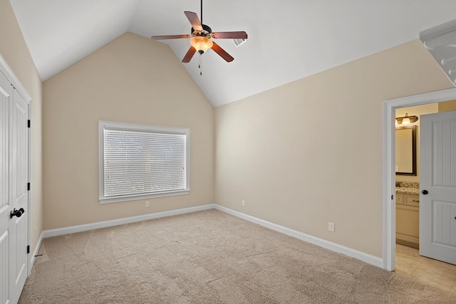 unfurnished bedroom featuring ensuite bath, vaulted ceiling, light carpet, a closet, and ceiling fan