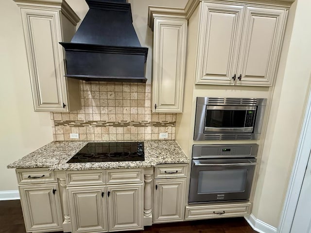 kitchen featuring wall oven, black electric stovetop, stainless steel microwave, light stone countertops, and custom exhaust hood