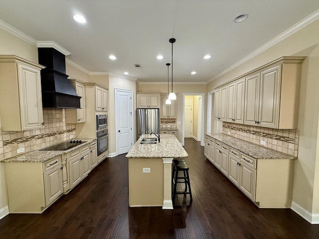 kitchen with pendant lighting, cream cabinets, black appliances, a center island with sink, and custom exhaust hood