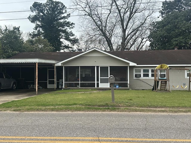 view of front of property featuring an attached carport, concrete driveway, a front yard, and a sunroom