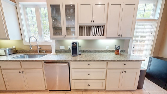 kitchen with dishwasher, glass insert cabinets, light stone counters, and a sink
