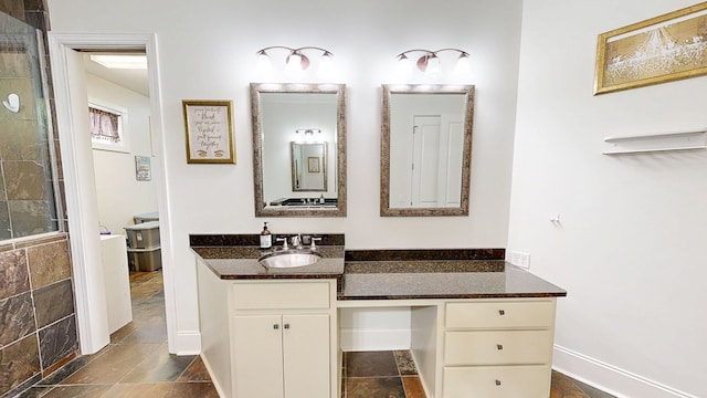 bathroom featuring a tile shower, baseboards, stone finish floor, and vanity