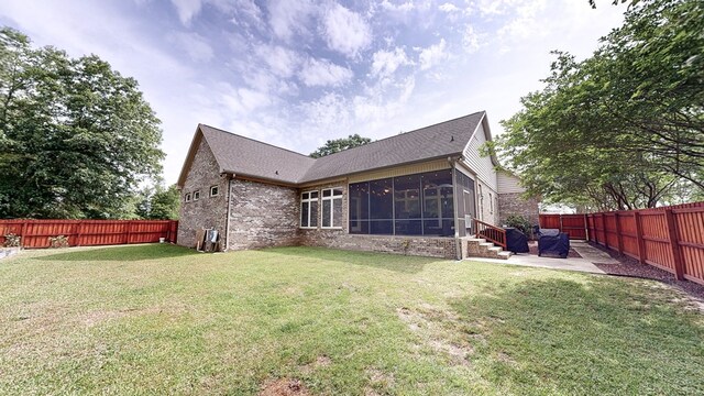back of property with a fenced backyard, a sunroom, a patio area, and a yard