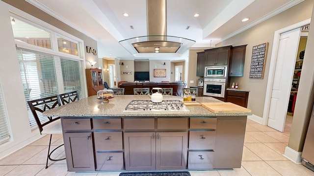 kitchen with stainless steel appliances, island range hood, ornamental molding, light tile patterned flooring, and a center island