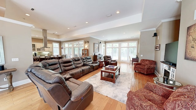 living area featuring crown molding, light wood-style floors, a tray ceiling, visible vents, and recessed lighting