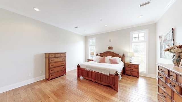 bedroom featuring baseboards, ornamental molding, light wood finished floors, and visible vents