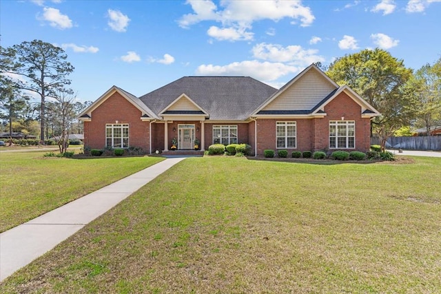 view of front of house featuring brick siding, fence, and a front lawn