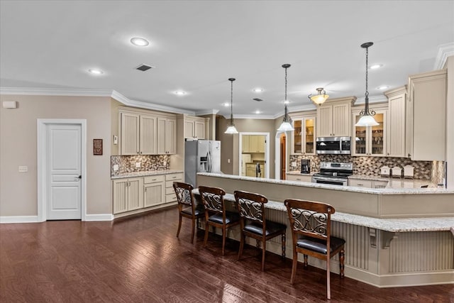 kitchen featuring crown molding, cream cabinetry, a peninsula, appliances with stainless steel finishes, and glass insert cabinets
