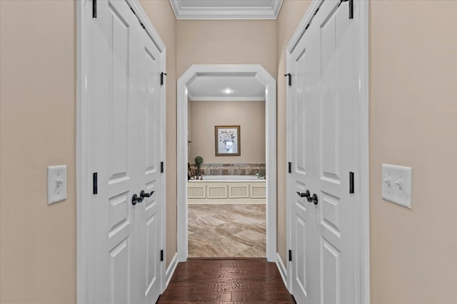 hall featuring arched walkways, a barn door, ornamental molding, and dark wood finished floors