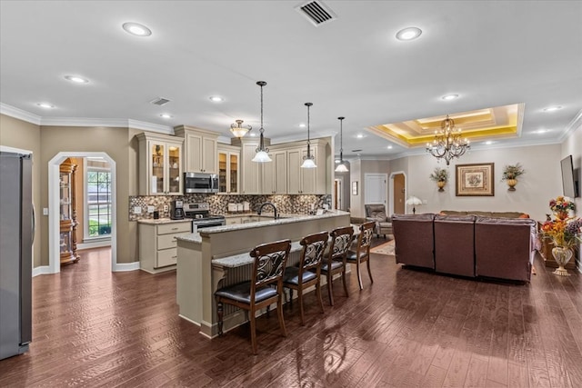kitchen with open floor plan, cream cabinets, arched walkways, visible vents, and appliances with stainless steel finishes