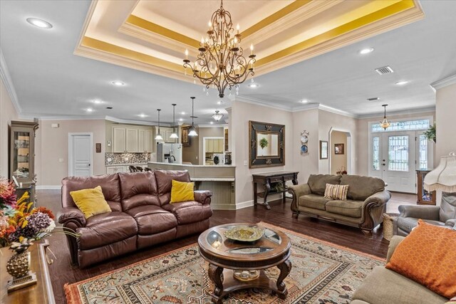living room featuring a chandelier, wood finished floors, recessed lighting, arched walkways, and a tray ceiling