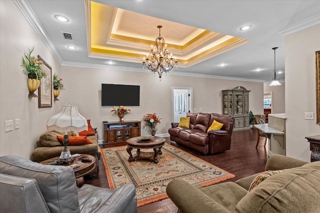 living room featuring ornamental molding, a chandelier, a raised ceiling, visible vents, and wood finished floors