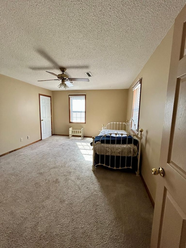 unfurnished bedroom with a textured ceiling, carpet floors, and ceiling fan