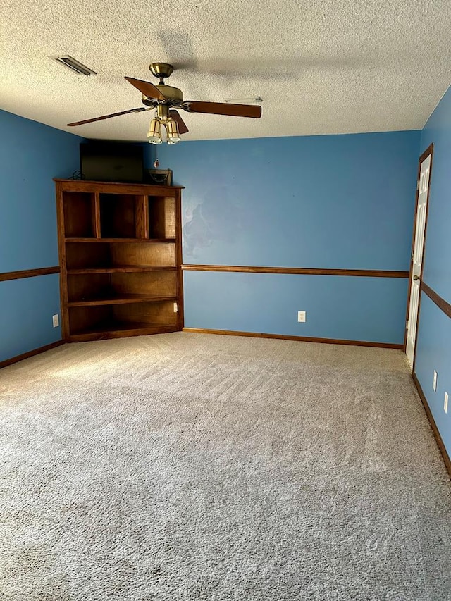 carpeted empty room featuring ceiling fan and a textured ceiling