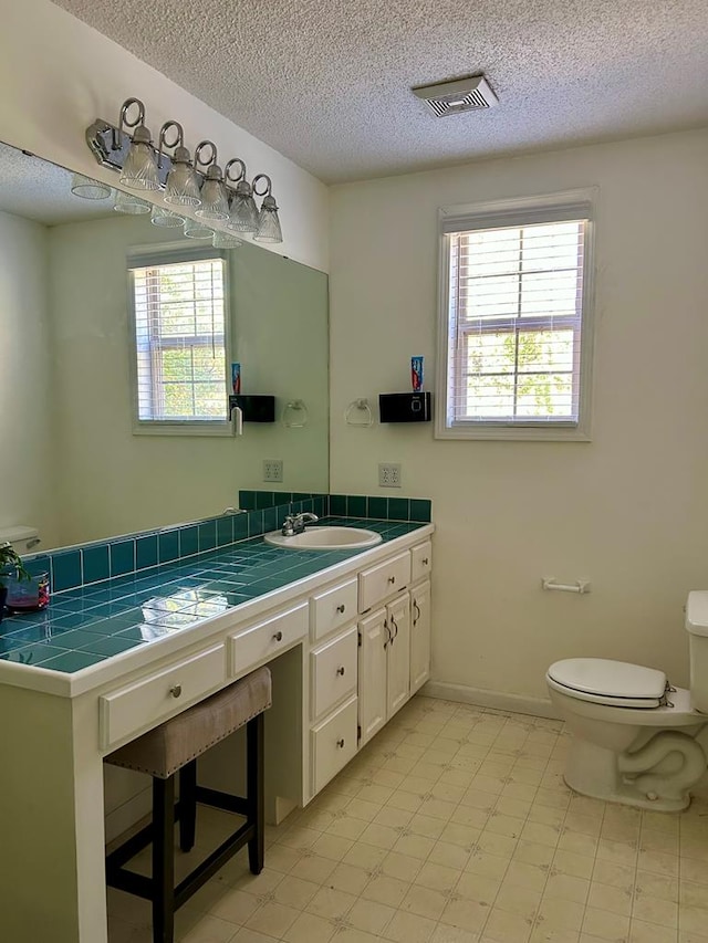 bathroom with a textured ceiling, vanity, and toilet