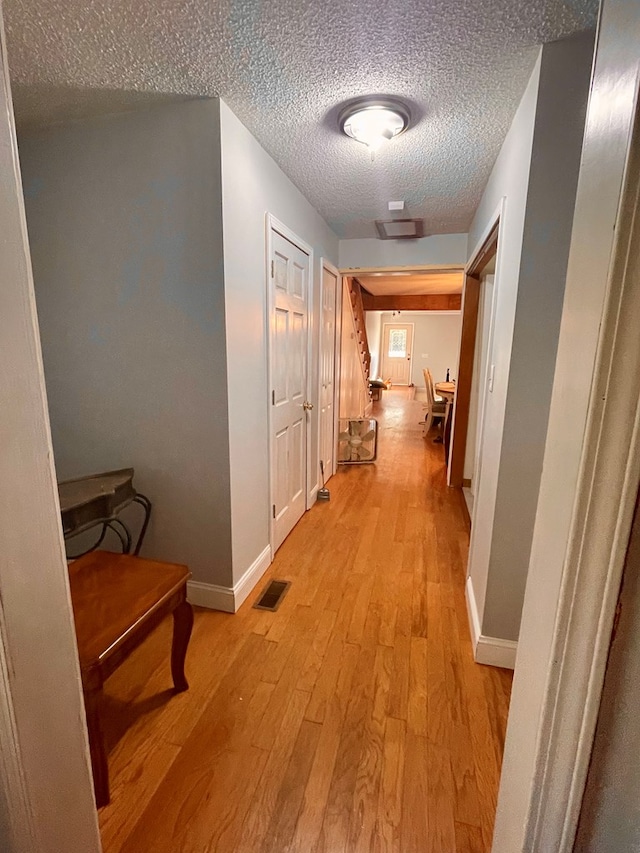 corridor featuring light hardwood / wood-style flooring and a textured ceiling