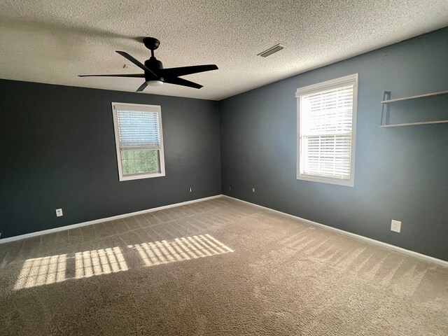 carpeted empty room featuring ceiling fan and a textured ceiling