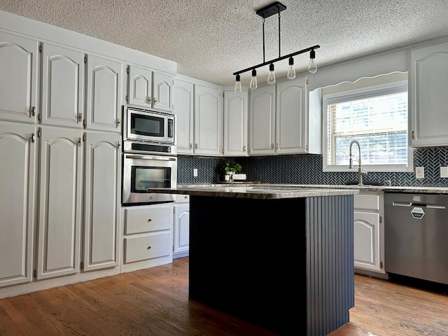 kitchen with white cabinets, appliances with stainless steel finishes, light wood-type flooring, and sink