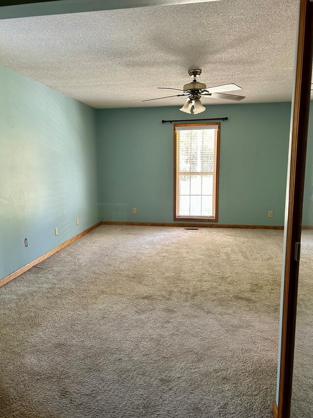 empty room with a textured ceiling, carpet floors, and ceiling fan