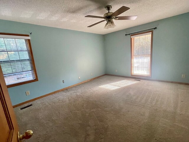 carpeted empty room with ceiling fan and a textured ceiling