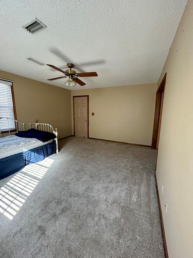 unfurnished bedroom with a textured ceiling, light colored carpet, and ceiling fan