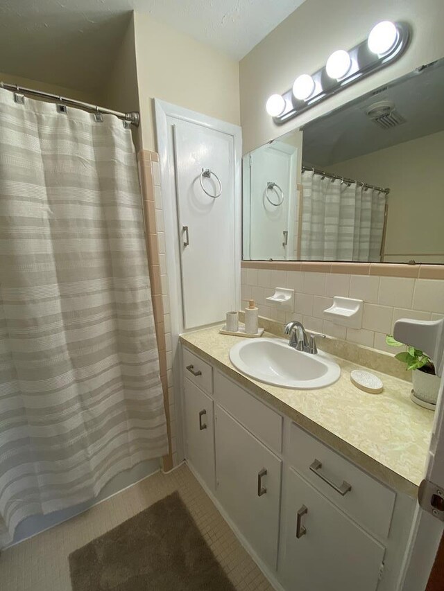 bathroom with curtained shower, tile patterned floors, backsplash, vanity, and tile walls