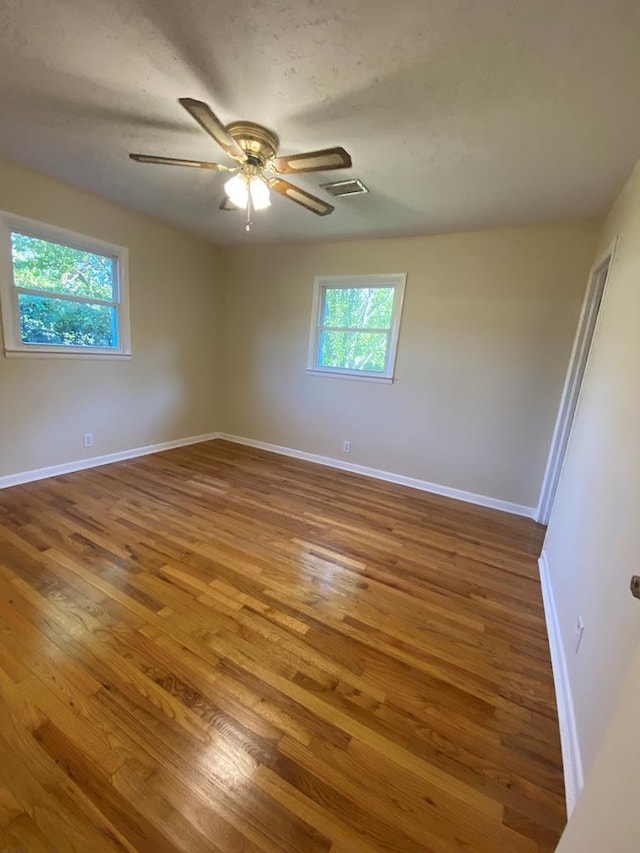 empty room featuring hardwood / wood-style floors, a wealth of natural light, and ceiling fan