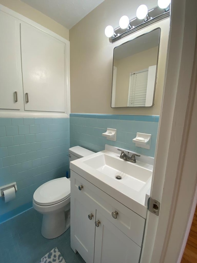 bathroom featuring tile patterned floors, vanity, tile walls, and toilet