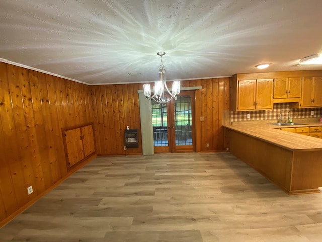 kitchen with tasteful backsplash, kitchen peninsula, light hardwood / wood-style flooring, and decorative light fixtures