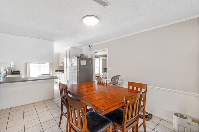 tiled dining room featuring a textured ceiling, sink, and crown molding