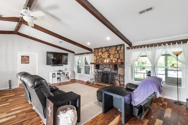 living room with vaulted ceiling with beams, ceiling fan, a stone fireplace, and wood-type flooring