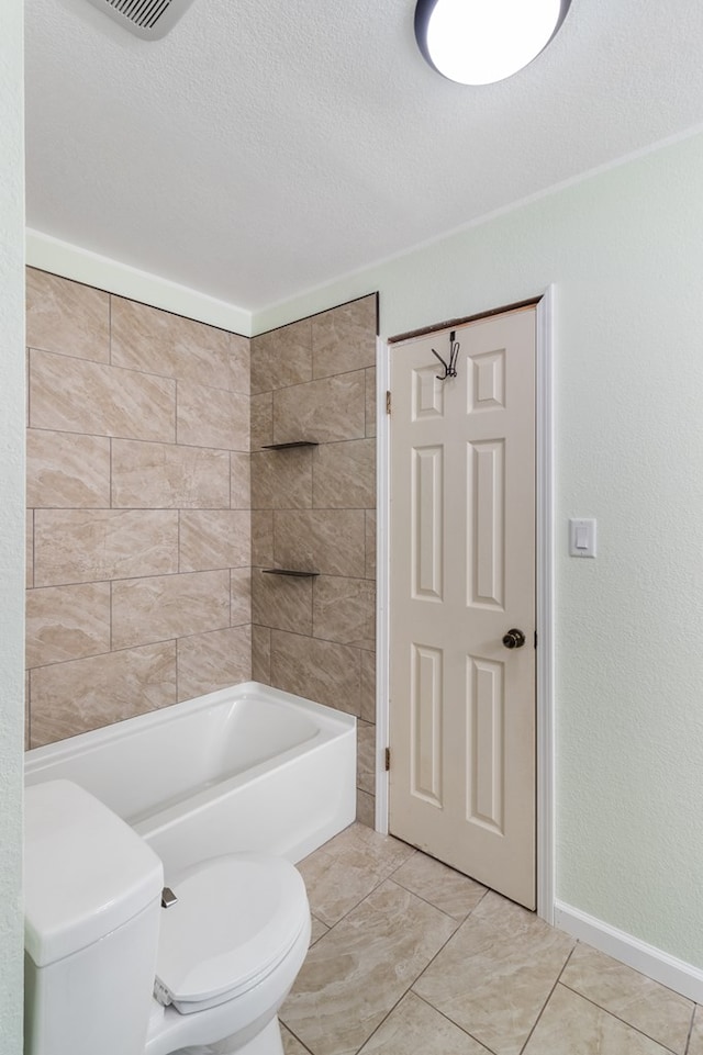 bathroom with tile patterned flooring, tiled shower / bath combo, toilet, and a textured ceiling