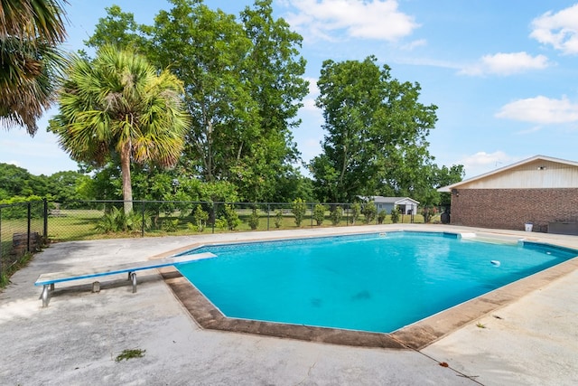 view of pool with a diving board and a patio