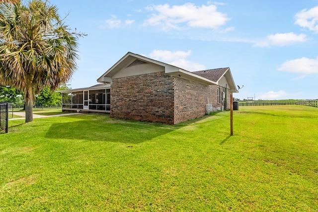 view of side of property with a sunroom and a yard