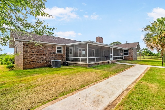 rear view of property featuring central air condition unit, a sunroom, and a yard