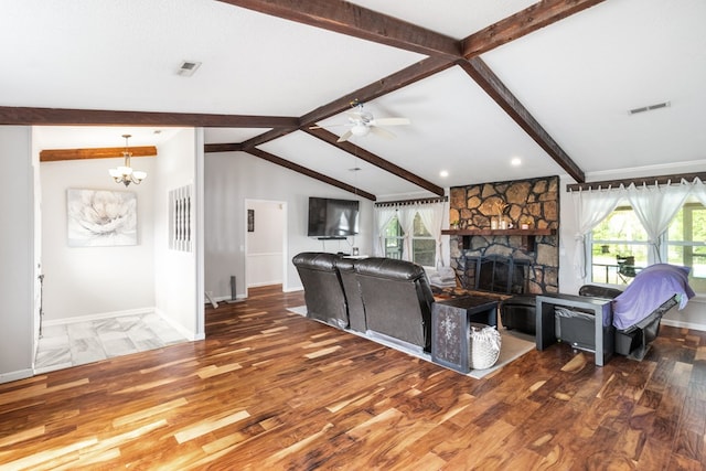 living room with hardwood / wood-style floors, lofted ceiling with beams, a stone fireplace, and ceiling fan with notable chandelier