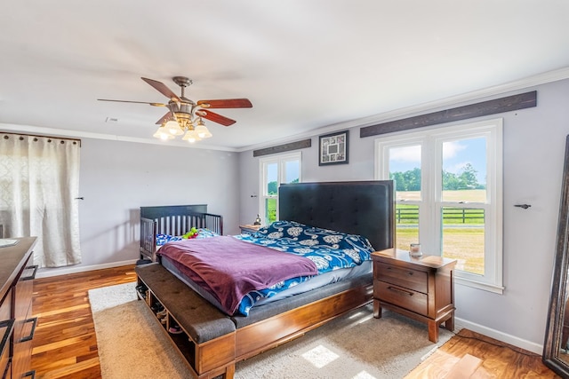 bedroom featuring ceiling fan, light wood-type flooring, and multiple windows