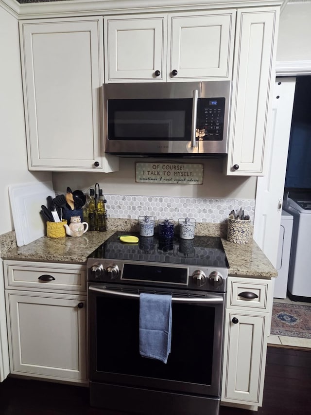 kitchen with light stone countertops, white cabinets, dark wood-style floors, independent washer and dryer, and stainless steel appliances