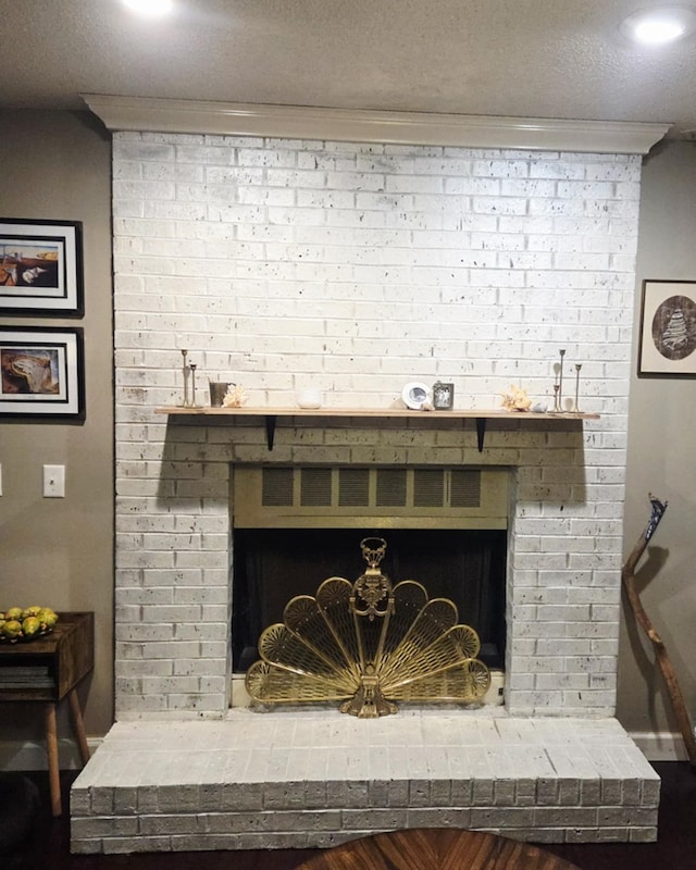 details featuring a brick fireplace, a textured ceiling, and crown molding