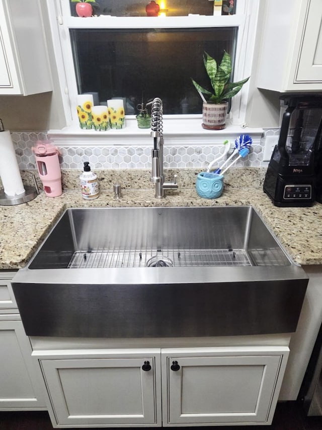 interior details with light stone counters, open shelves, a sink, decorative backsplash, and white cabinets