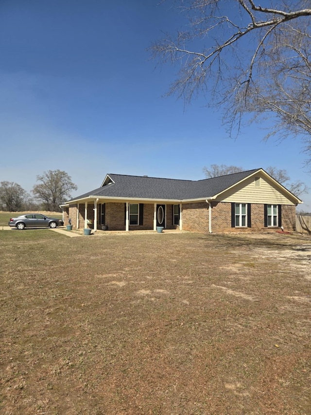 ranch-style house featuring brick siding, a front lawn, and roof with shingles