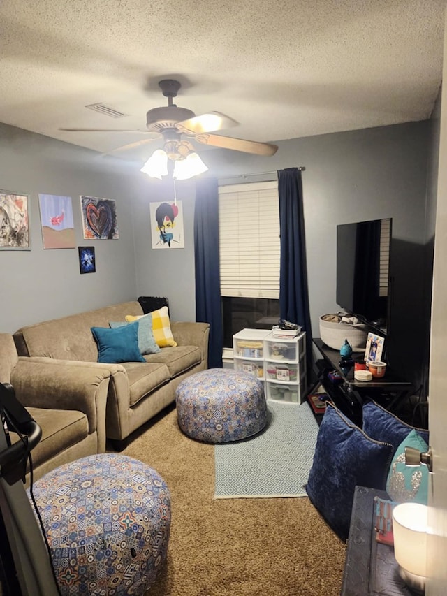 living area with a textured ceiling, carpet flooring, and ceiling fan