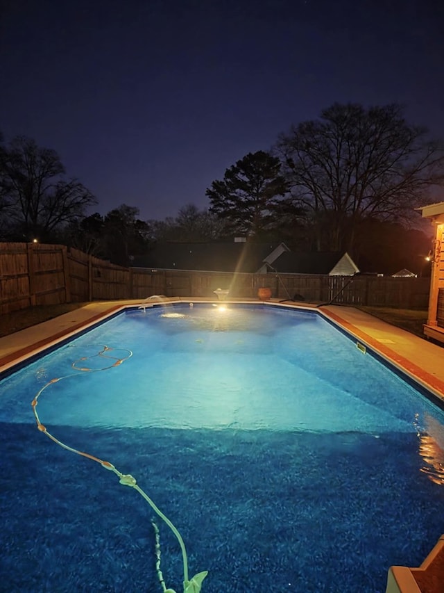 pool at night featuring a fenced in pool and a fenced backyard